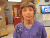 a young boy wearing a purple shirt with a sticker on it that says ' i 'm a nurse '