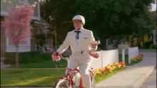 a man in a white suit is riding a bike down a sidewalk