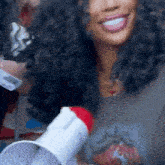 a woman with curly hair is smiling and holding a white megaphone