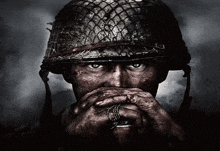 a close up of a soldier 's face with his hands on his mouth