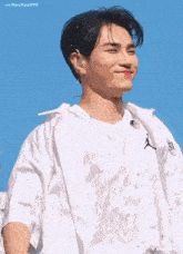 a young man wearing a white shirt and a white jacket is smiling .