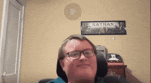 a man wearing glasses is smiling in front of a sign that says nathan on it