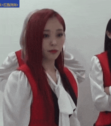 a woman with red hair is wearing a white shirt and red vest