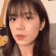 a close up of a woman 's face with a guitar behind her .