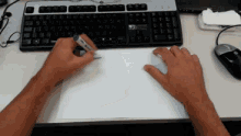 a person is writing on a piece of paper while using a keyboard and mouse