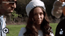 a woman wearing a white hat is standing in a field with a man .