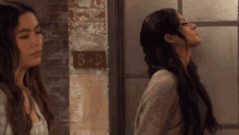 two women are standing next to each other in front of a wall with the number 8 on it