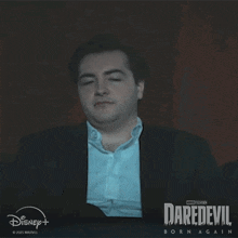 a man is smiling in front of a daredevil poster
