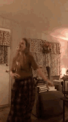 a woman is standing in a living room holding a glass of wine .