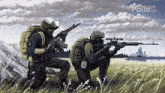 two soldiers are kneeling in a field with guns .