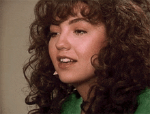 a close up of a woman with curly hair and a green shirt