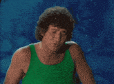 a man in a green tank top stands next to a mermaid piggy