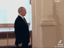 a man in a suit and tie is standing in front of a white wall .