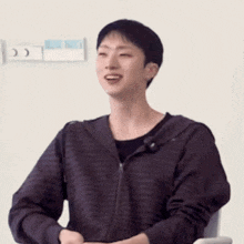 a young man wearing a striped hoodie is smiling while sitting in a chair