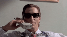 a man wearing sunglasses is talking on a phone with the words got it thanks