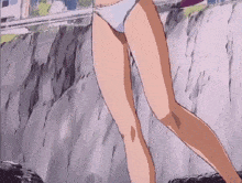 a woman in a bikini is standing on a rocky hillside .