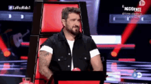 a man with a beard is sitting in a chair on a tv show called la voz kids 1
