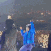 a man in a blue jacket is dancing on a stage in front of a crowd