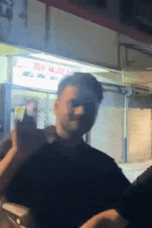 a man in a black shirt is standing in front of a building with a sign that says ' a ' on it