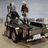 a man standing next to a trailer that has a license plate that says pue 8601