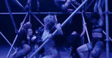 a group of dancers are dancing on a stage while hanging from a scaffolding .