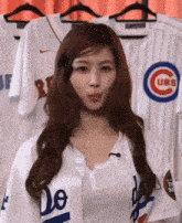 a woman wearing a dodgers jersey is standing in front of a row of cubs jerseys .