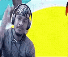 a man wearing headphones and a bandana is sitting in front of a yellow and blue background .