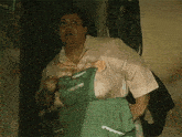 a woman in a pink shirt and green apron is standing in front of a wall