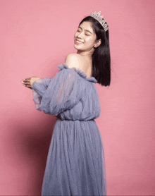 a woman wearing a tiara and a blue dress is smiling