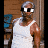 a man in a white tank top has sunglasses on his face
