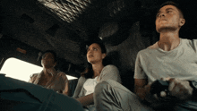 a man and two women are sitting in a car looking up at the sky
