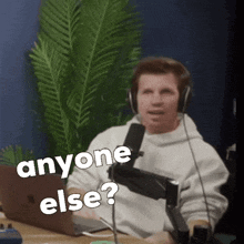 a man wearing headphones is sitting in front of a microphone with the words " anyone else " on the screen