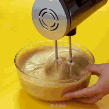 a person is mixing something in a bowl with a mixer and the word mr.cakes is on the yellow background