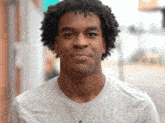 a man with curly hair wears a grey shirt
