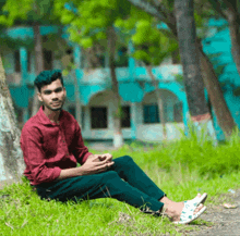 a man in a red shirt sits on the grass