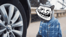 a troll face is on a cat 's head in front of a car wheel