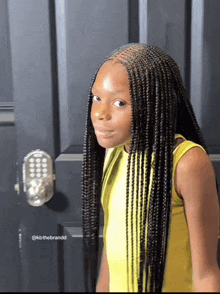 a young girl with braids in her hair is standing in front of a black door