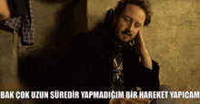a man with a beard is sitting on the floor with the words bak çok uzun suredir yapmadigim bir hareket yapicam