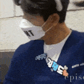 a man wearing a blue shirt and a mask with the word wt on it