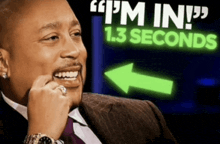 a man in a suit and tie smiles in front of a sign that says i 'm in 1.3 seconds