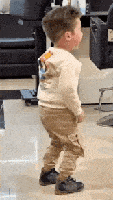 a little boy is standing in a room in a hair salon .