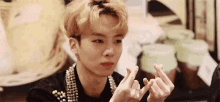 a young man is making a heart with his fingers .