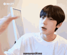 a young man in a white shirt is looking at a mirror .