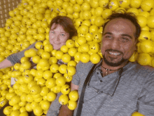 a man and a woman are standing in a pile of yellow smiley face balls