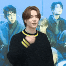 a man wearing a black sweater with yellow stripes on the sleeves is standing in front of a group of young men