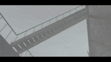 a black and white photo of a bridge with stairs leading up to it .
