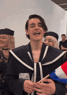 a man in a sailor costume is smiling and holding a french flag