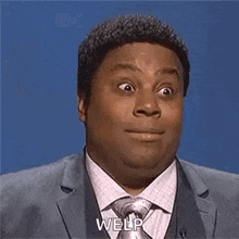 a man in a suit and tie is making a funny face while talking on a microphone .