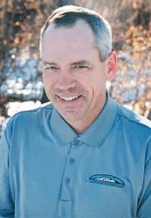a man wearing a blue polo shirt with a logo on the sleeve
