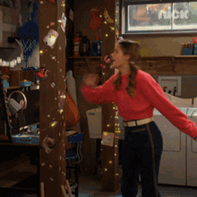 a girl in a red sweater is standing in a room with a nick logo on the wall